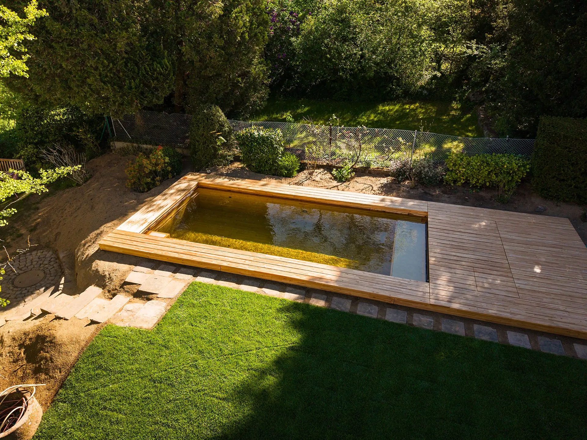 HOLC® Naturpool aus Lärchenholz mit klarem Wasser, eingebettet in einen privaten Garten